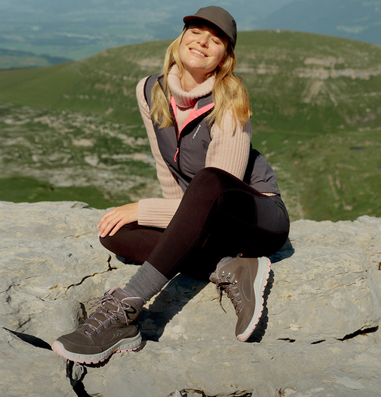 Frau in Trekking-Schuhen sitzt auf einem Berg